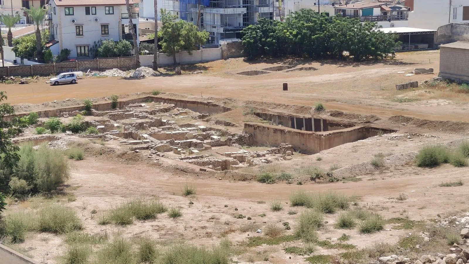 The excavation trench at Kition, Larnaca, cut down through the strata, with the modern town continuing directly behind it.